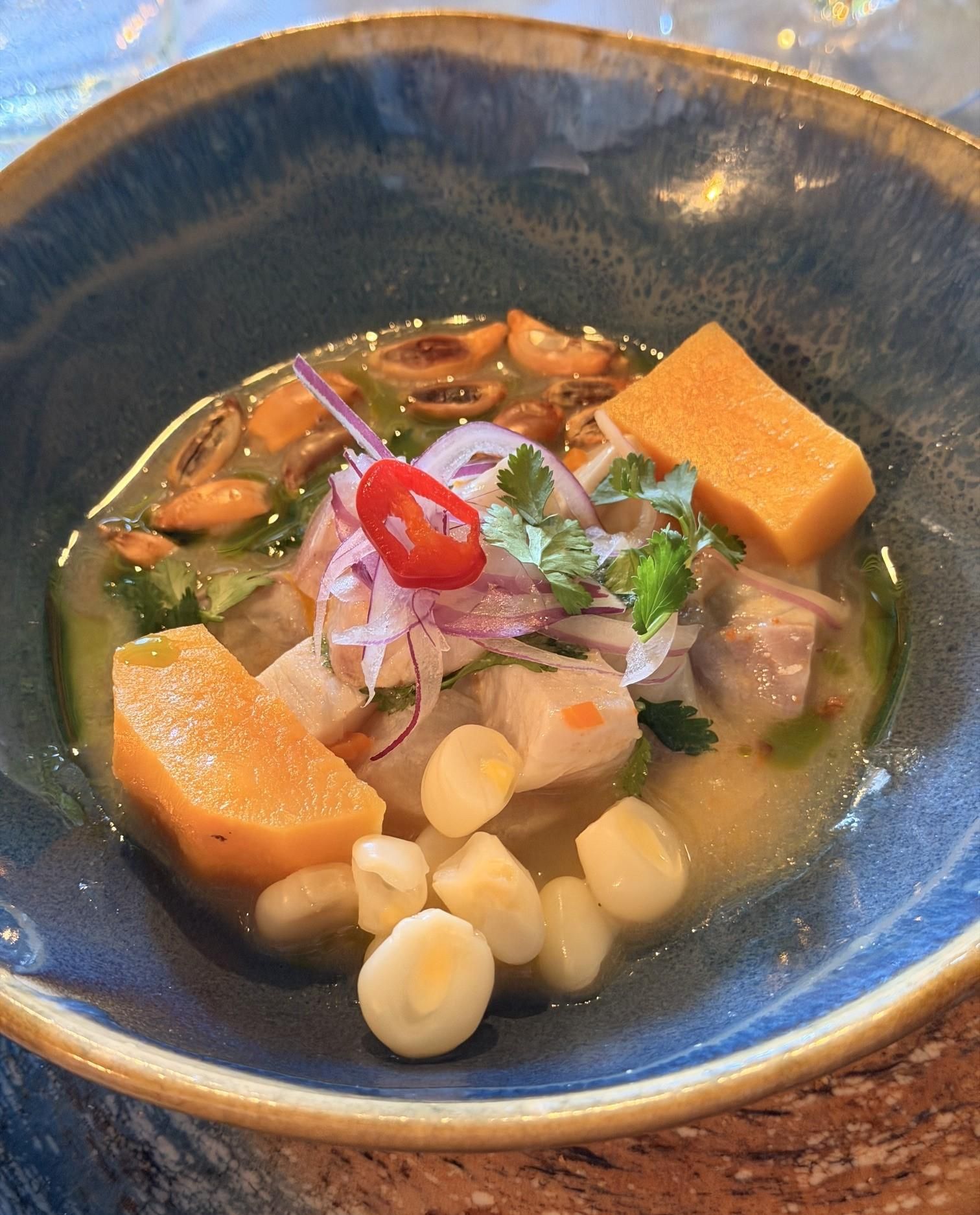 Ceviche de pescado blanco con ají limo, batata, cebolla, choclo, maíz chulpi y brotes de cilantro
