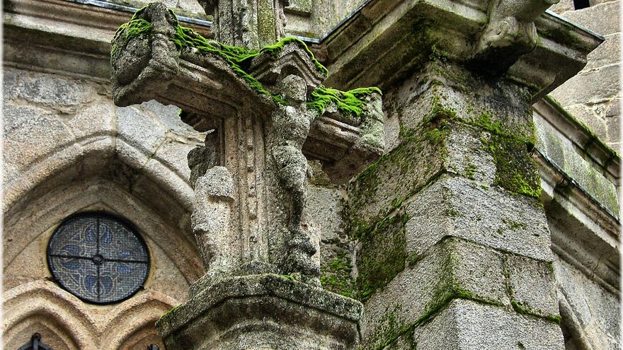 El musgo cubre un crucerio situado junto a los muros de la Catedral de Lugo.