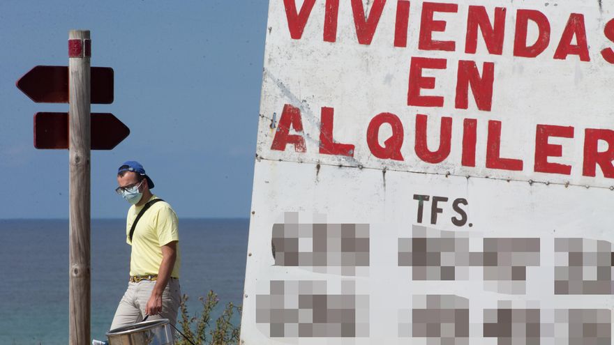 Un hombre camina junto a un cartel de viviendas en alquiler