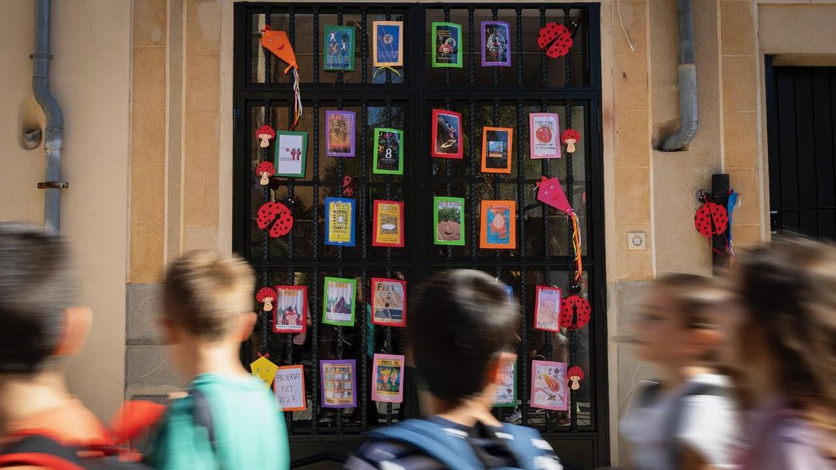 Un grupo de escolares pasa por delante de una casa engalanada con carteles del festival.