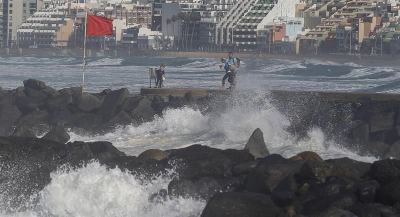 Varias personas se toman fotografías en el paseo de la playa de Las Canteras en Las Palmas de Gran Canaria con el oleaje de fondo. EFE/Elvira Urquijo A.
