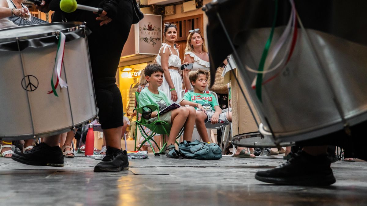 Un grup de nens en l'asseguda mentre escolten la batucada.