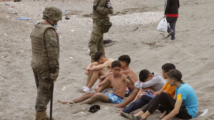 Miembros del Ejército de Tierra vigilan a un grupo de inmigrantes menores este martes, tras cruzar uno de los espigones fronterizos de Ceuta. EFE/Reduan