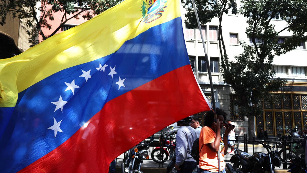 Imagen de archivo (03/01/2026) de un simpatizante del oficialismo con una bandera de Venezuela este sábado en inmediaciones del Palacio de Miraflores en Caracas (Venezuela).