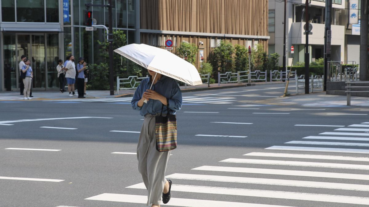 Una mujer se protege con paraguas del calor mientra cruza en una calle de Tokio, que este jueves afrontó una de sus jornadas más calurosas, en medio de una ola de temperaturas extremas que ha dejado 14 muertos y un récord de más de 10.000 hospitalizados en una semana. EFE/ Pilar Bernal Zamora