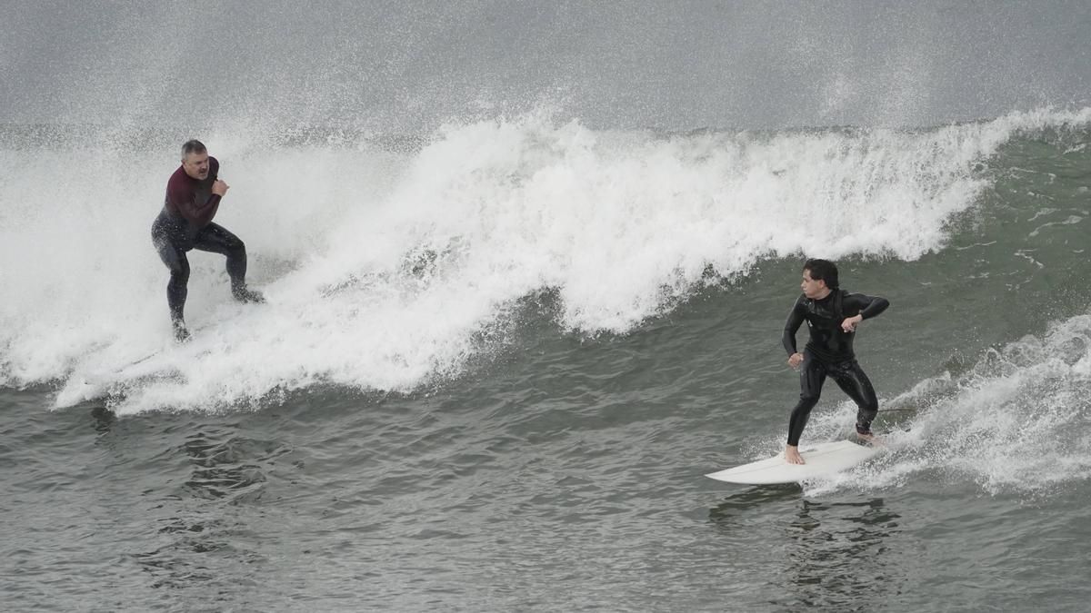 Surfistas entre las olas en la playa de San Lorenzo esta mañana.