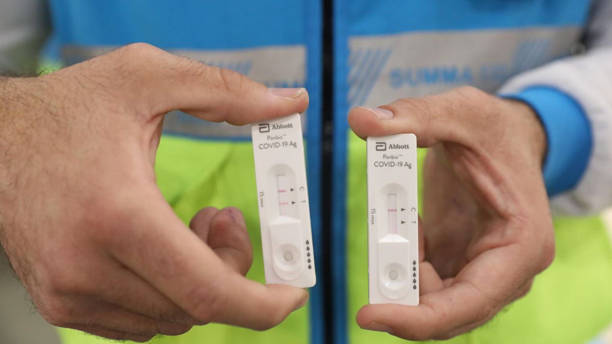 Un trabajador sanitario muestra el resultado positivo (izquierda) y negativo (derecha) de dos de los tests de antígenos que están realizando a vecinos del distrito de Vallecas, en el centro cultural Lope de Vega en Madrid (España) a 13 de octubre de 2020.