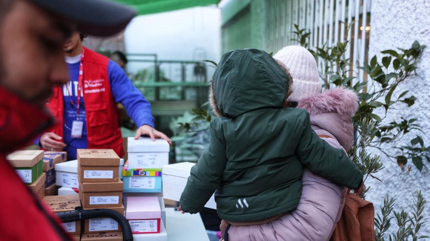 Una mujer recibe ropa de invierno y zapatos que se entrega a familias en riesgo de vulnerabilidad.