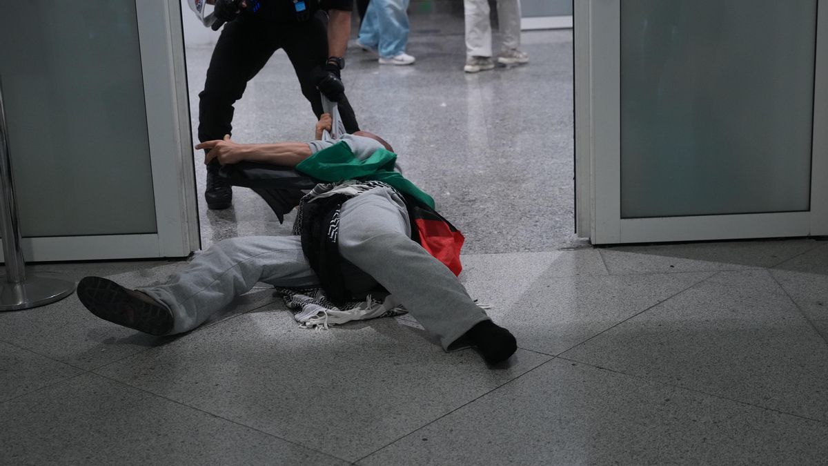 Un agente arrastra a una persona por el suelo del aeropuerto de Loiu