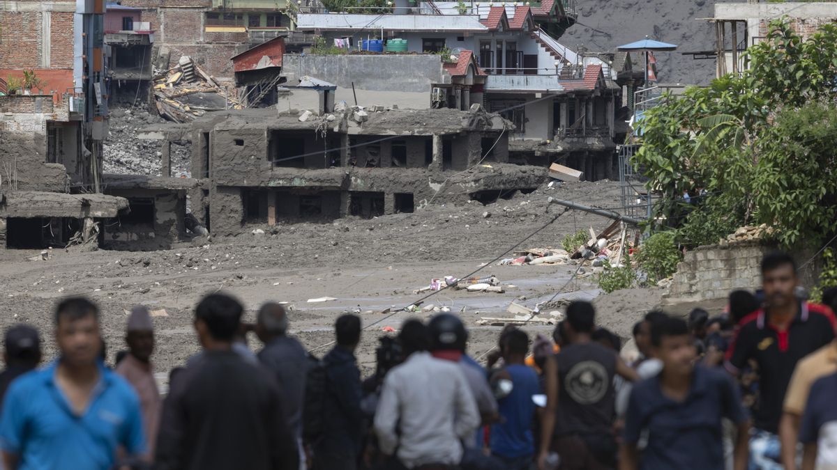 People watch as floodwaters sweep through Trishuli Bazar following a flash flood, in Nuwakot district, Nepal, 26 August 2026. Several people were killed and multiple others were reported missing after a massive flash flood swept through Rasuwa and Nuwakot districts causing widespread destruction to settlements and infrastructure, according to local authorities. (Inundaciones)