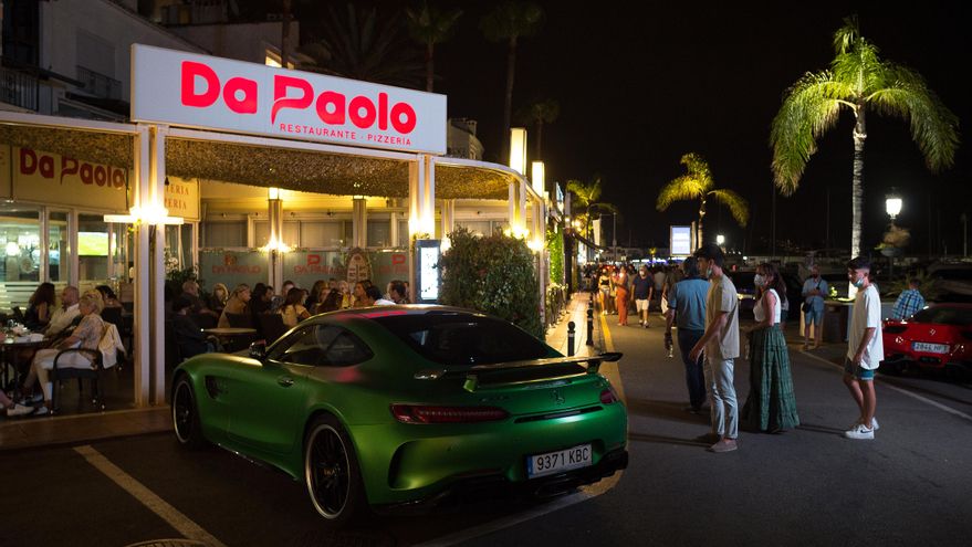 Un grupo de personas observan un coche de lujo en el paseo marítimo de Puerto Banús.