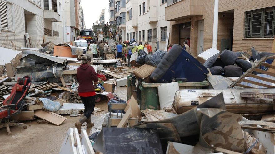 Vecinos de Paiporta y militares cargan escombros y enseres inservibles en un camión militar durante las labores de limpieza y reconstrucción de las calles, este lunes.