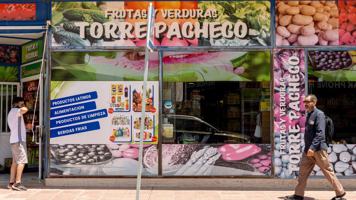 Dos hombres pasan por la puerta de un comercio en la localidad murciana de Torre Pacheco. EFE/Marcial Guillén