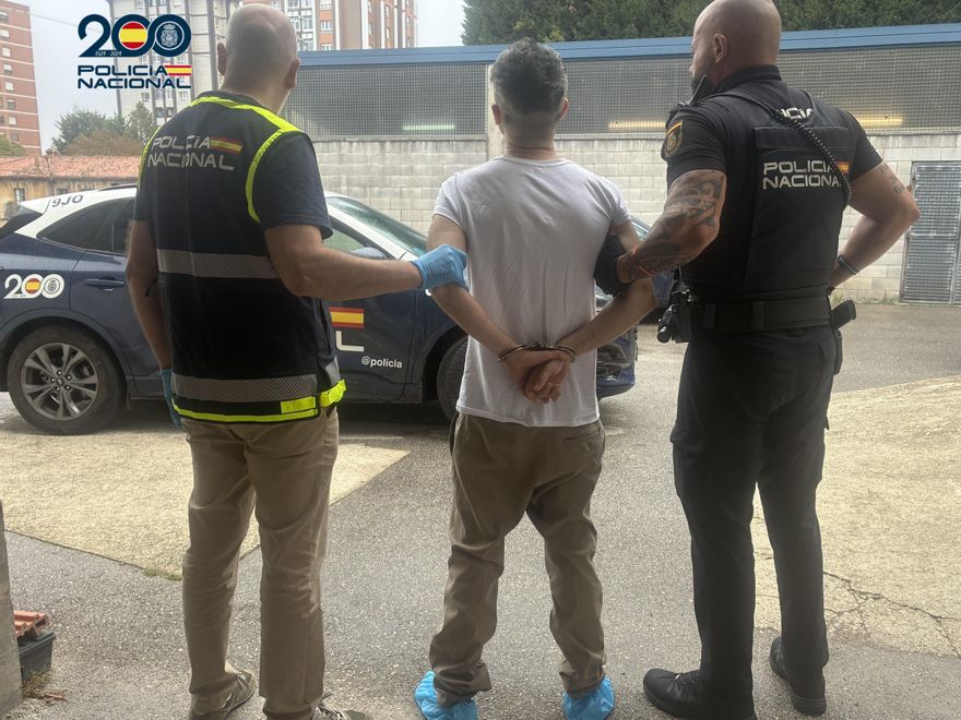 Momento en el que los agentes de la Policía Nacional trasladan detenido al hombre acusado del homicidio y posterior incendio provocado en la vivienda del barrio de Pumarín, en Oviedo/Uviéu.