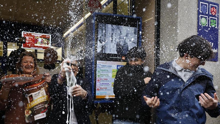 Varias personas celebran a las puertas de la administración de loterías del número 10 de la calle Barquillo, en Madrid, donde se ha vendido íntegramente el 70.048, el segundo premio del Sorteo Extraordinario de la Lotería de Navidad.
