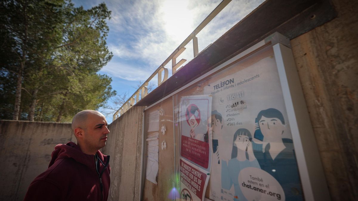 El profesor mira los carteles a la entrada del instituto.