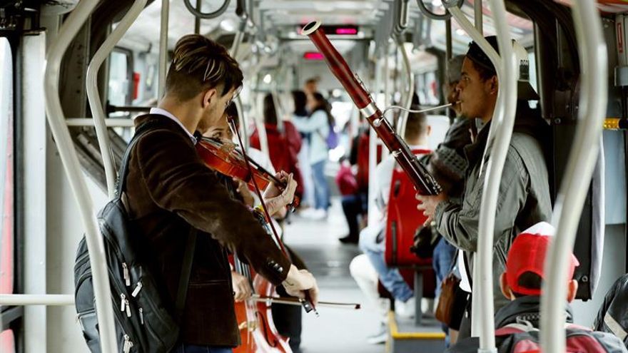 Fotografía fechada el 27 de septiembre de 2019 que muestra a los músicos venezolanos Omar Quintero (violín) y Alexis Velásquez (fagot), mientras actúan en un autobús de transporte público en Bogotá (Colombia).