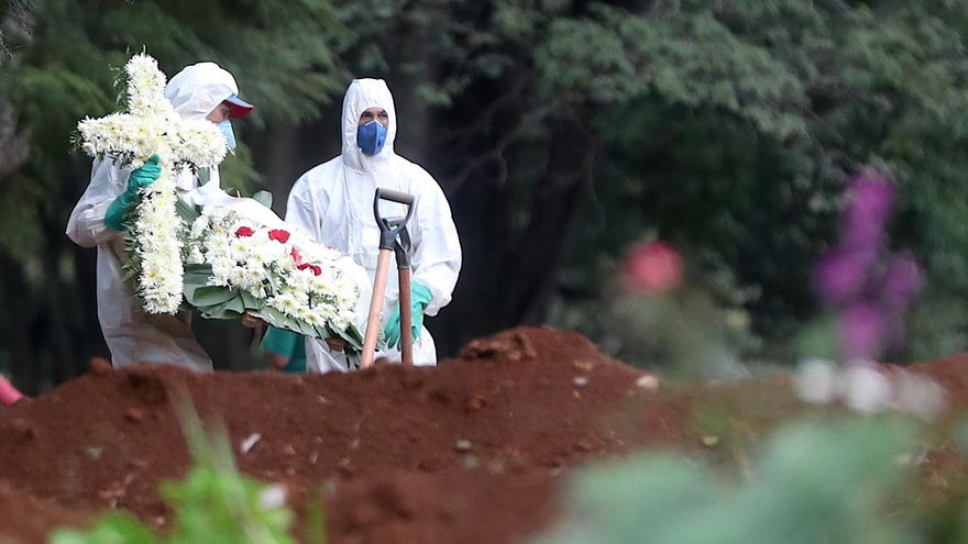 Empleados del servicio funerario entierran a una víctima de COVID-19 en el cementerio de Vila Formosa, situado en Sao Paulo (Brasil).