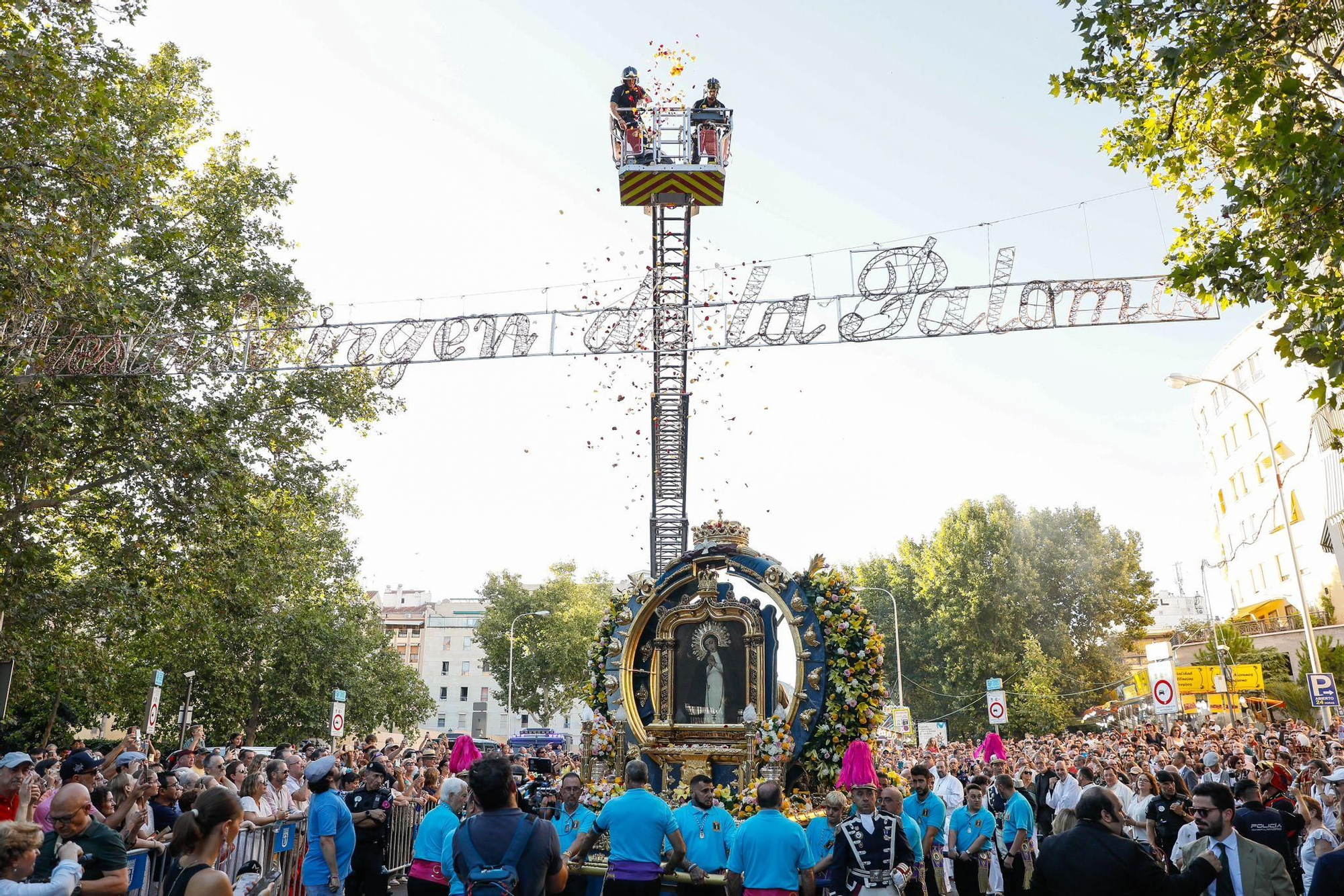 Bomberos lanzando flores a la Virgen de la Paloma durante la procesión de 2024