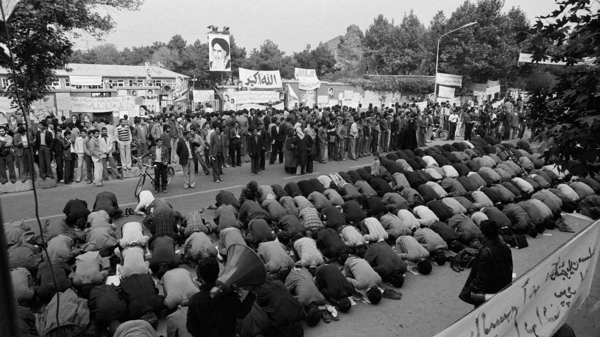 Un grupo de personas reza frente a la embajada de EEUU, donde 54 rehenes se encuentran retenidos por estudiantes el 7 de noviembre de 1979 en Teherán.