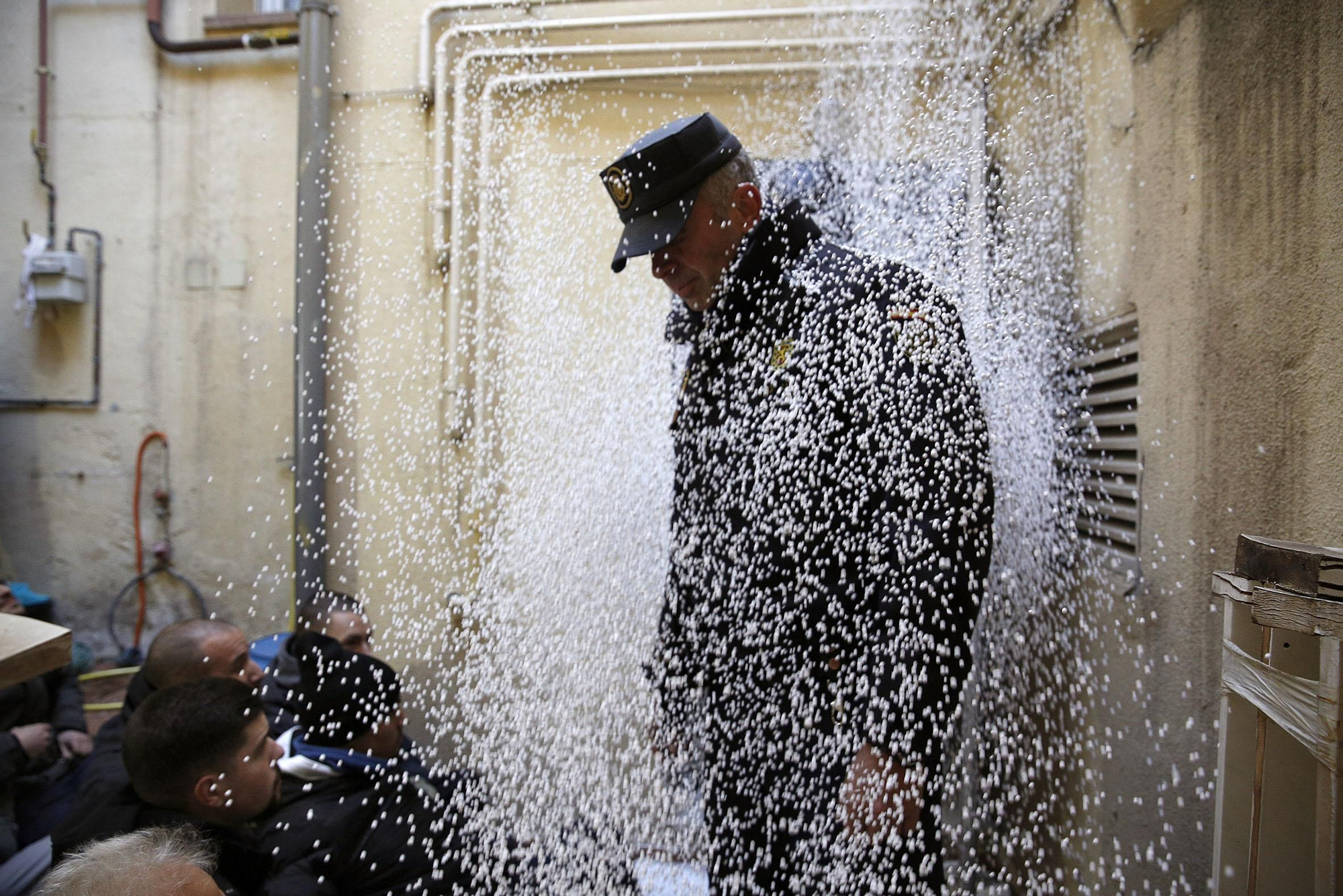 Un policía nacional cubierto por bolitas de poliespán lanzadas por los activistas antidesahucios cuando los agentes entraron al patio delantero de la vivienda.