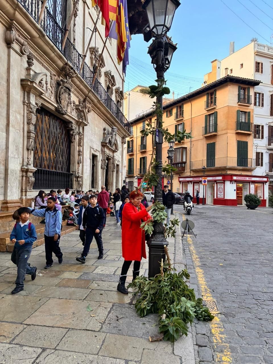 Una mujer coloca restos de poda en el palo de una farola situada frente al Ajuntament de Palma, donde continuó la protesta.
