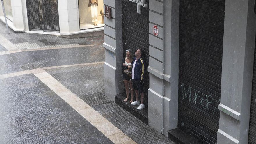 Dos personas, refugiadas de la lluvia este martes por la mañana en la calle Castillo de Santa Cruz de Tenerife.