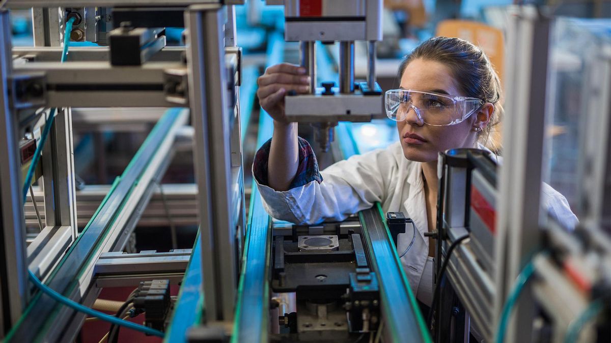 Trabajadora de control de calidad análisis de parte de la máquina en el laboratorio