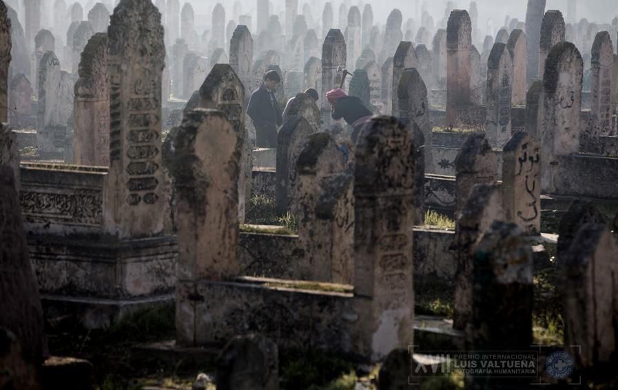 Un hombre está cavando una tumba en un cementerio en Alepo, mientras que los niños miran./ Niclas Hammarström