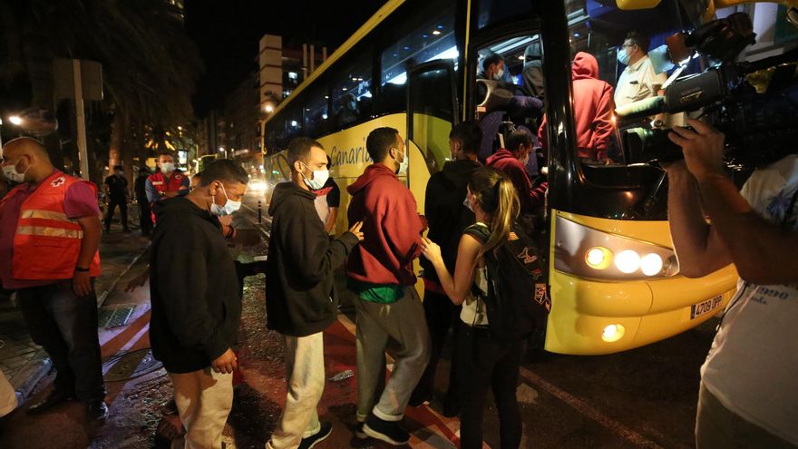 Migrantes subiendo en las guaguas que anoche les trasladaron a una plaza alojativa.