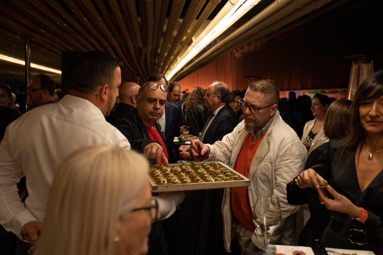 Asistentes a la gala cogiendo canapés de una bandeja en el cóctel organizado por David López
