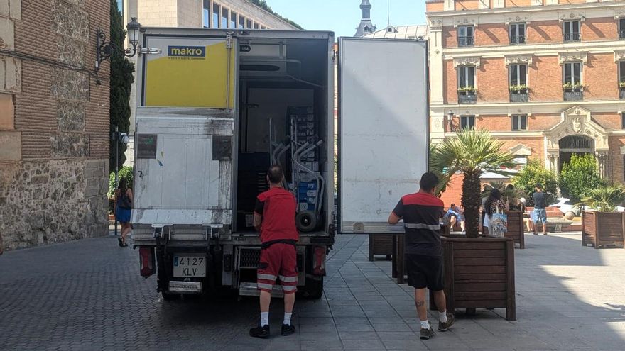Dos transportistas se resguardan a la sombra mientras trabajan en el centro