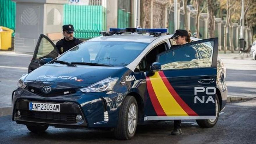 Dos agentes de la Policía Nacional se suben a un vehículo del cuerpo.