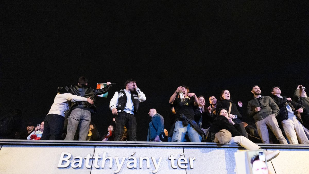 Jóvenes subidos al edificio del metro celebran los resultados electorales.