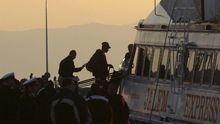 Refugiados son escoltados a un ferri en el puerto de Mytilene en la isla de Lesbos en Grecia este lunes