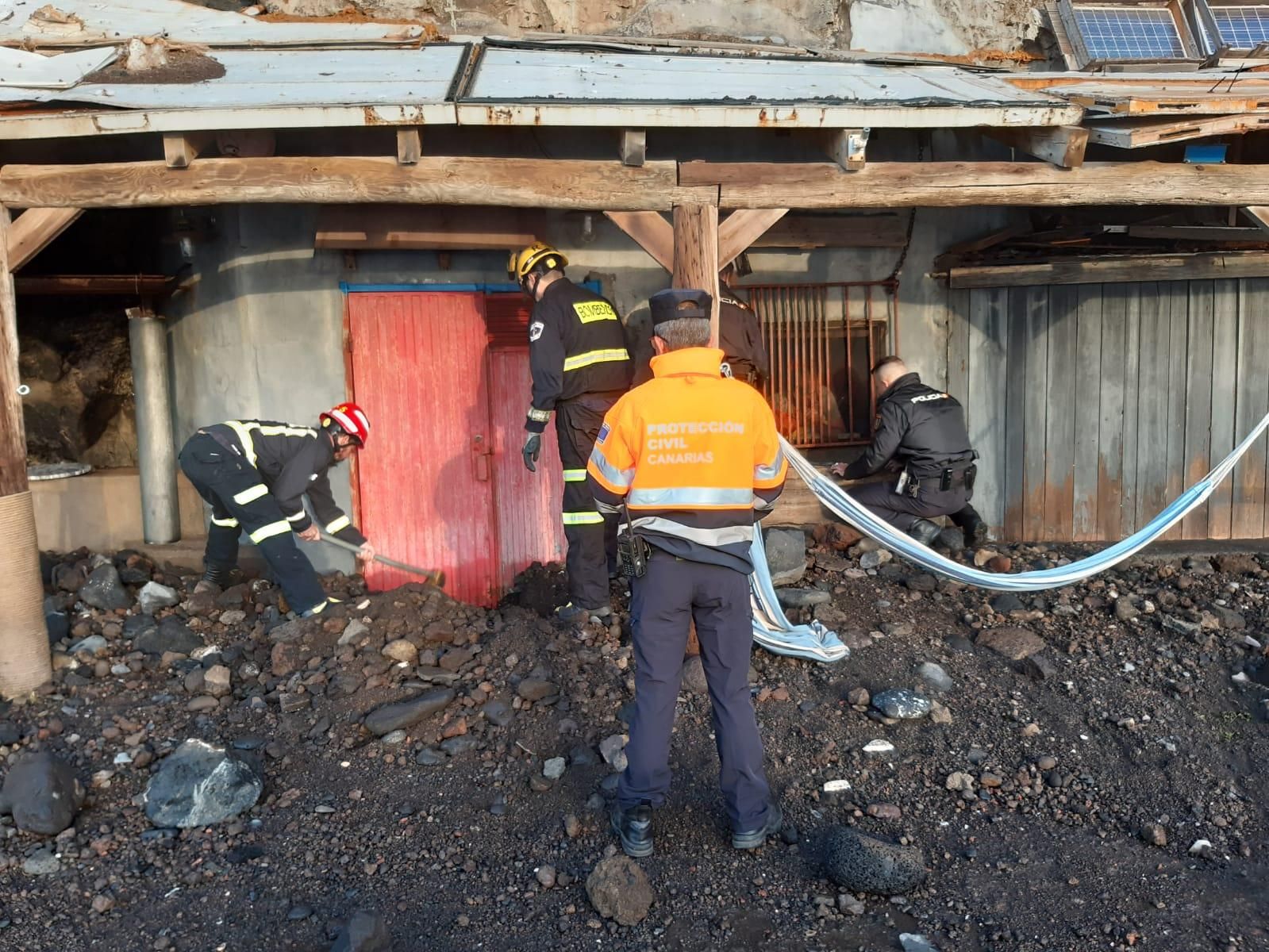 En la imagen, los bomberos retiran escombro de la puerta de la chabola. BOMBEROS LA PALMA