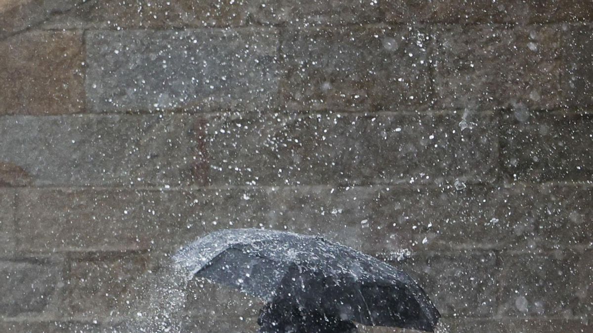 Una persona se protege de la fuerte lluvia en la plaza del Obradoiro, este lunes en Santiago de Compostela