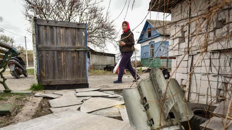 Una mujer camina junto a una parte de un misil en el patio de una casa privada en la aldea de Kukhari, en la zona de Kiev, Ucrania. EFE/Oleg Petrasyuk