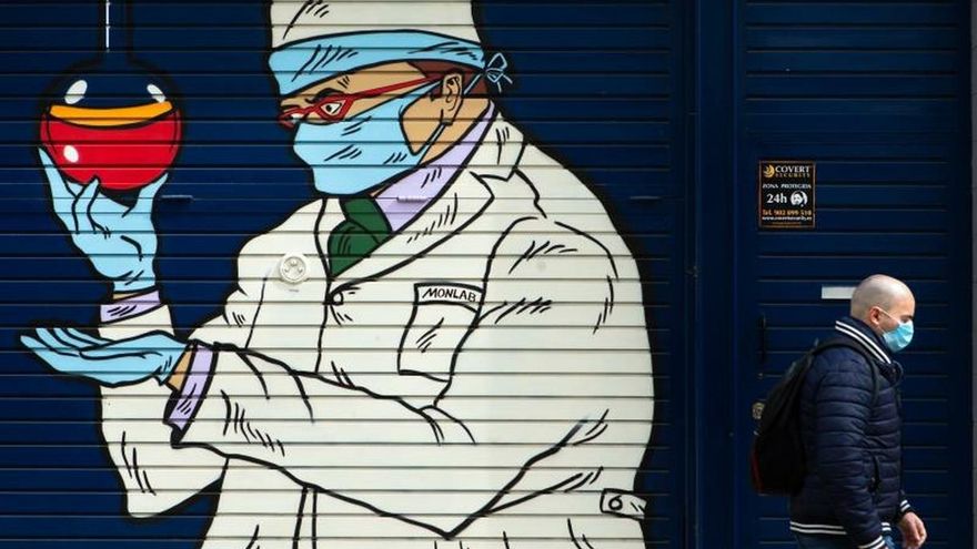 Un hombre camina ante un grafitti en una calle de Barcelona.