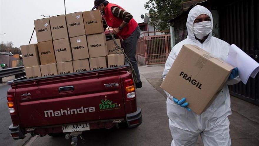 Trabajadores municipales de la comuna de San Ramón reparten cajas con alimentos básicos a familias vulnerables afectadas por las consecuencias de la cuarentena obligatoria decretada para detener el avance de la COVID-19, este jueves, en Santiago (Chile).