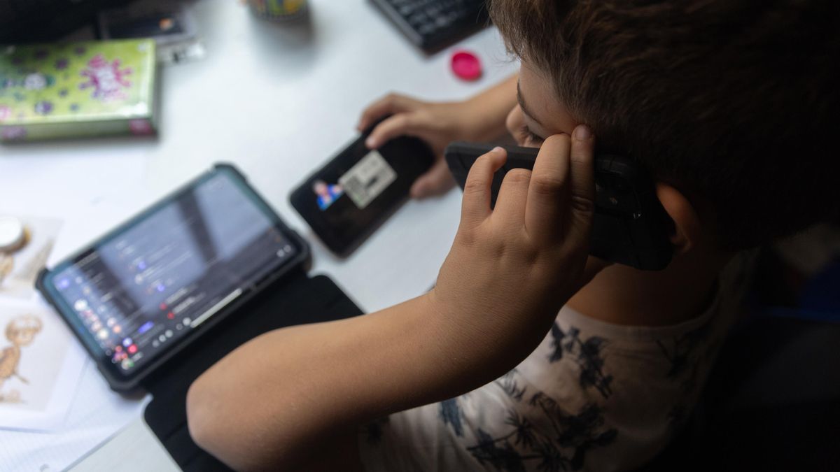 Un niño con el teléfono móvil y una tablet.
