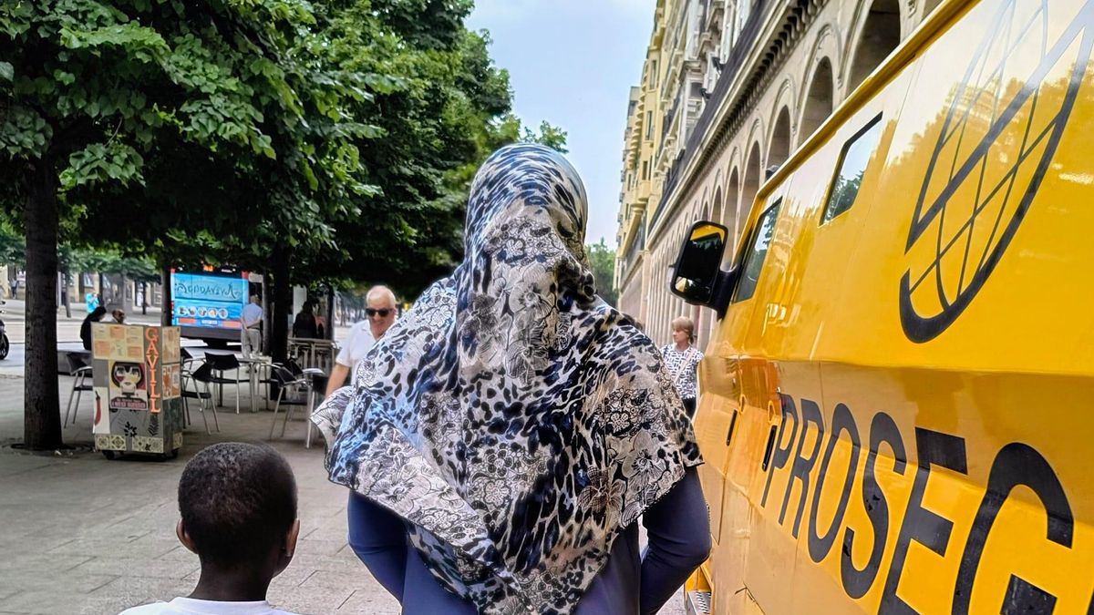 Furgón de recogida de dinero sobre la acera de Independencia y mujer y niños pasando al lado.