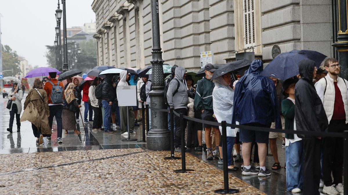 Turistas se protegen de la lluvia a la entrada del Palacio Real en Madrid, en una foto de archivo