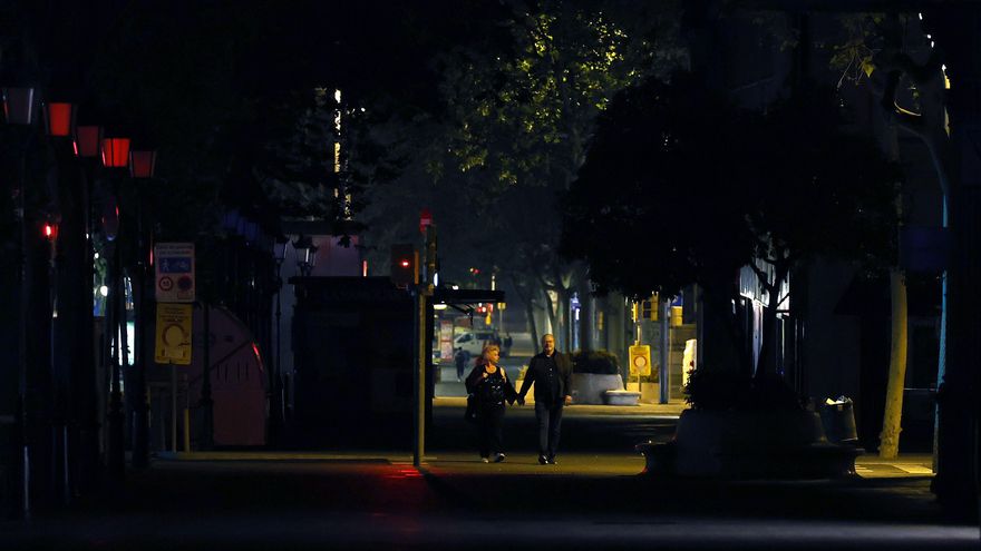 Una pareja camina por el Paseo de Gracia de Barcelona que esta madrugada permanece en semioscuridad por el corte de suministro eléctrico que ha afectado este lunes a España y que ha dejado sin servicio el metro y el tranvía de Barcelona y todas las líneas de ferrocarril, y sin red de teléfonos móviles ni internet. EFE/Alberto Estévez