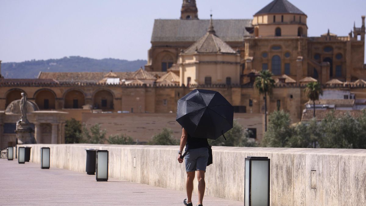 Una persona usa un paraguas para protegerse del sol mientras paseo por el Puente Romano de Córdoba este viernes, jornada marcada por avisos naranja a causa de la ola de calor.