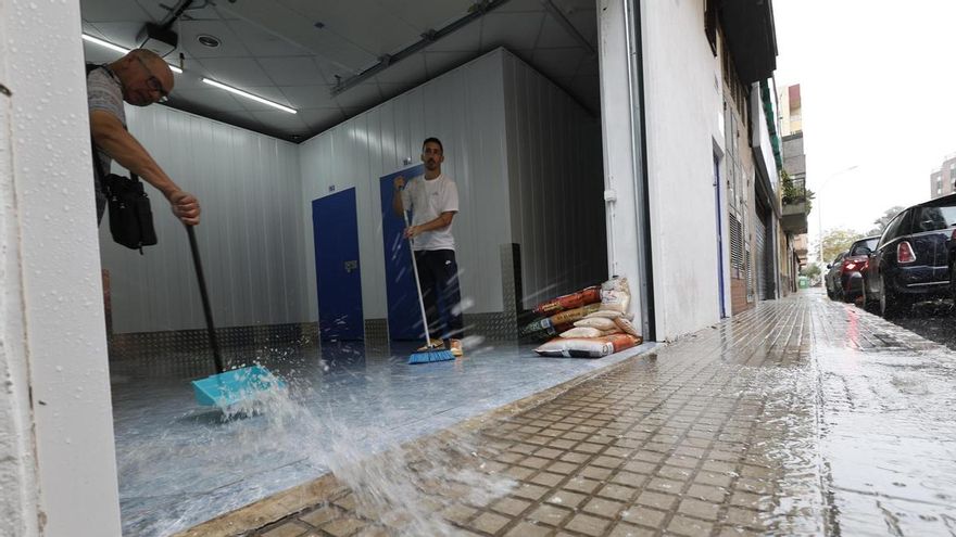 Vecinos retiran agua de unos trasteros tras las fuertes lluvias este domingo en Gandia.