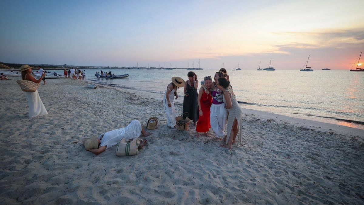 Unas turistas se hacen fotos durante la puesta de sol tras salir de la fiesta de un chiringuito situado en una playa donde apareció un cadáver el pasado enero.