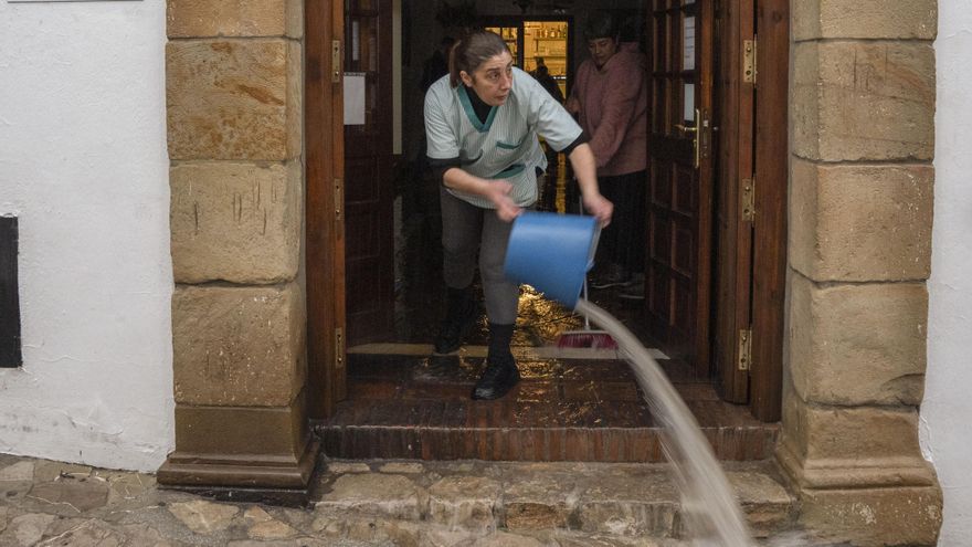 Vecinos de Grazalema intentan achicar agua de sus casa y locales debido a las intensas lluvias que se registran este miércoles en la localidad gaditana.