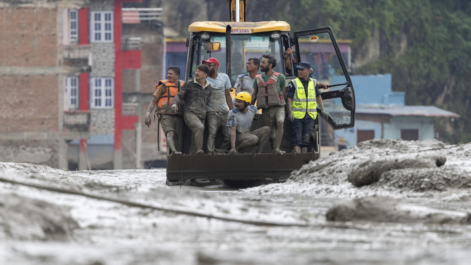 Equipos de rescate se desplazan en una excavadora en la aldea de Devighat.