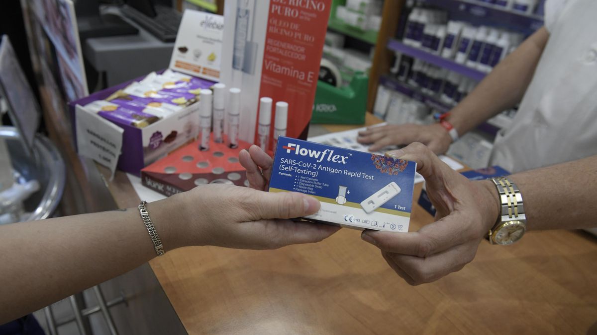Un farmacéutico enseña un test de antígenos de detección del COVID-19 en una farmacia.